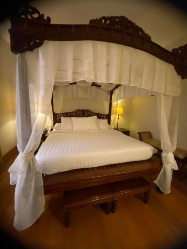 a bedroom with a large canopy bed with white sheets at Hotel Salcedo De Vigan in Vigan