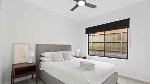 a white bedroom with a bed and a window at Sams House in Metung