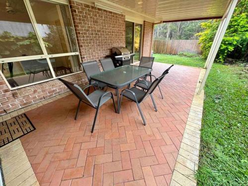 a patio with a table and chairs and a grill at Sandstone Point and Bribie Beaches in Sandstone Point