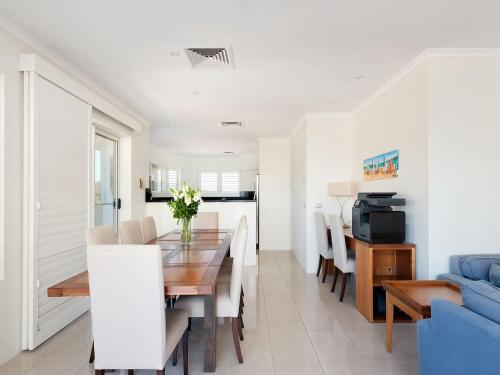 a dining room and living room with a table and chairs at Views More Views Sub Penthouse at The Breakwater in Shoal Bay in Shoal Bay