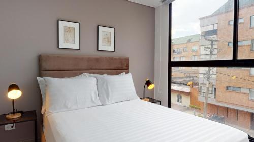 een slaapkamer met een bed en een groot raam bij Harmony Unicentro Suites Kappa in Bogota