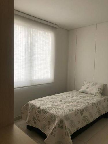 a white bedroom with a bed and a window at Apartamento familiar in Sincelejo