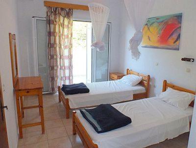 a room with three beds and a window at House Anastasia in Agios Georgios Pagon