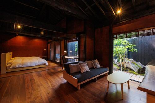 um quarto com uma cama, um sofá e uma cadeira em 浜崎の宿萩別邸 em Hagi