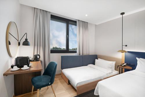 a hotel room with a bed and a chair at Hilton Garden Inn Bucharest Airport in Otopeni