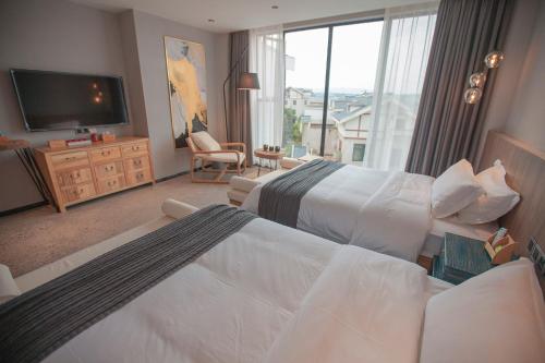 a hotel room with two beds and a flat screen tv at 张家界惹莲心栖墅·精品民宿 in Zhangjiajie