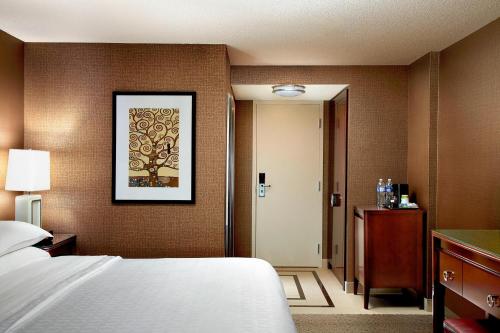a hotel room with a bed and a door to a hallway at Sheraton Cavalier Calgary Hotel in Calgary