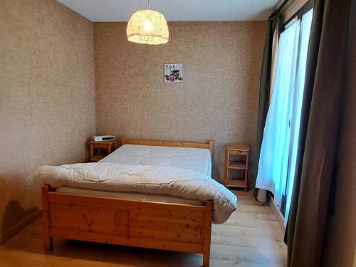 a bedroom with a bed and a window and a chandelier at Confortable T2 avec balcon et parking à Jausiers - FR-1-165A-174 in Jausiers