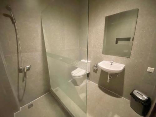 a bathroom with a shower and a toilet and a sink at The Grand Palace Hotel Malang in Malang