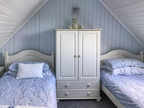 a bedroom with two beds and a white cabinet at The House On The Slip - Uk43806 in Kylerhea