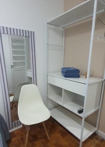 um armário branco com uma cadeira branca e uma prateleira branca em Kit Pé na Areia em Santos
