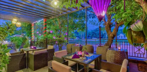 a restaurant with tables and chairs and a tree at Royal Riverside Hoi An Hotel & Spa in Hoi An