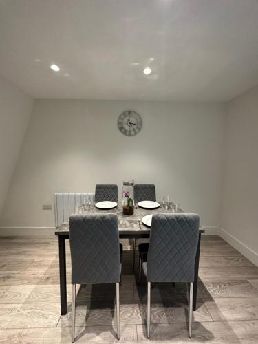 einem Esstisch mit 2 Stühlen und einer Uhr an der Wand in der Unterkunft Home-like 1-BR flat in Victoria in London