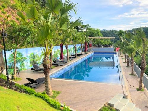 - une piscine bordée de palmiers à côté d'un complexe dans l'établissement BlueHome Villa, à Hòa Bình