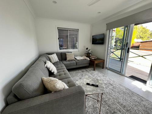 a living room with a couch and a table at Berrara Brand New Beach House in Berrara