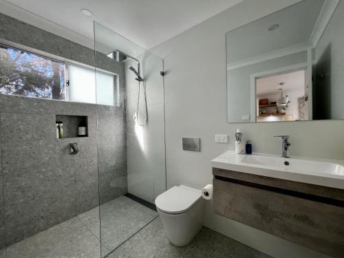 a bathroom with a toilet and a sink and a shower at Berrara Brand New Beach House in Berrara