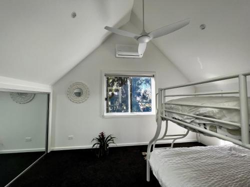 a bedroom with a bunk bed and a ceiling fan at Berrara Brand New Beach House in Berrara