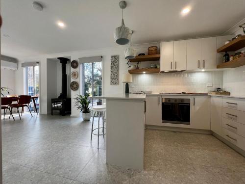 a kitchen with white cabinets and a living room at Berrara Brand New Beach House in Berrara