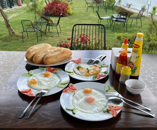 een tafel met drie borden eieren en brood erop bij METRO HOMESTAY in Bao Loc