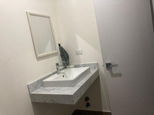 a white bathroom with a sink and a mirror at Cómodo y cálido departamento en San Isidro in Lima