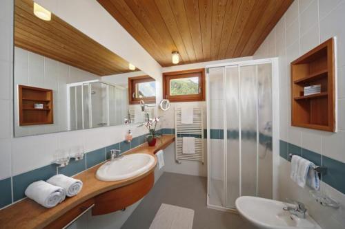 ein großes Bad mit 2 Waschbecken und einer Dusche in der Unterkunft Hotel Edelweiss in Mals im Vinschgau