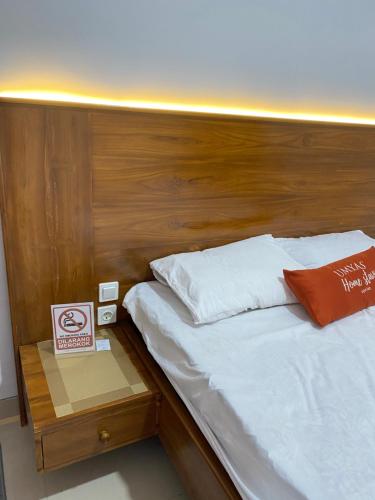 a bed with a wooden headboard next to a table at Umyas Hotel Syariah in Nganjuk