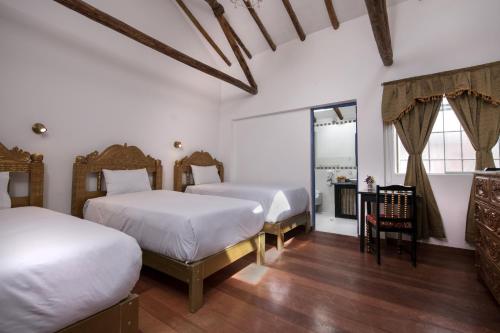 クスコにあるInkarri Regocijo Plazaの白い壁とウッドフロアの客室で、ベッド2台が備わります。