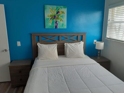 een slaapkamer met een bed met een blauwe muur bij Sandalwood Beach Resort in St Pete Beach