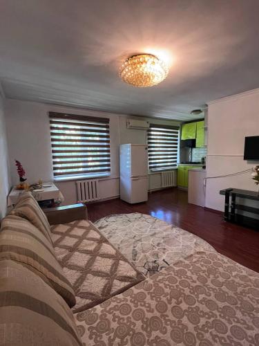 uma sala de estar com um sofá e uma cozinha em Уютные апартаменты em Shymkent