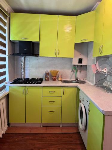 a kitchen with bright yellow cabinets and a washing machine at Уютные апартаменты in Shymkent