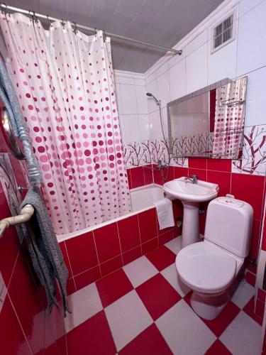 a red and white bathroom with a toilet and a sink at Уютные апартаменты in Shymkent