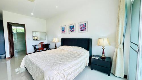 a white bedroom with a bed and two lamps at Baan Ing Khao in Pak Chong