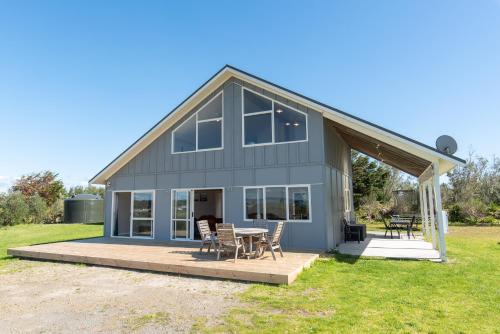 a house with a table and chairs on a deck at Tokerau Magic - Karikari Peninsula Holiday Home in Kaitaia