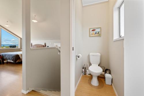 a white bathroom with a toilet and a bedroom at Tokerau Magic - Karikari Peninsula Holiday Home in Kaitaia