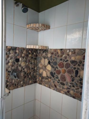 a bathroom with a shower with rocks on the wall at Hotel La Escalinata in Copan Ruinas