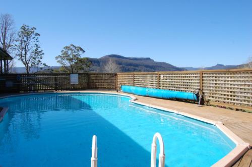 uma grande piscina com água azul em frente a uma cerca em The Big Bell Farm em Kangaroo Valley