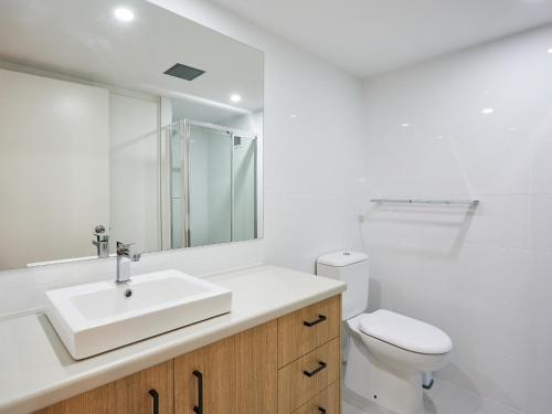 a white bathroom with a sink and a toilet at Horizons Holiday Apartments - OFFICIAL in Gold Coast