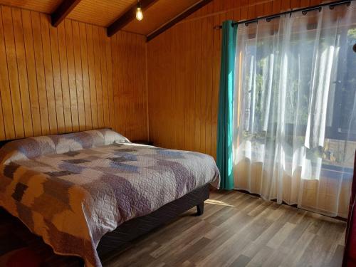 um quarto com uma cama ao lado de uma janela em CABAÑAS 88 Y 8 em Coñaripe