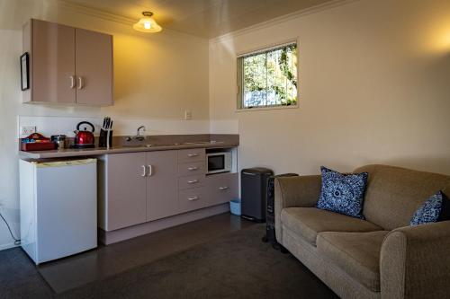 a living room with a couch and a kitchen at Amber Court Motel in Te Anau