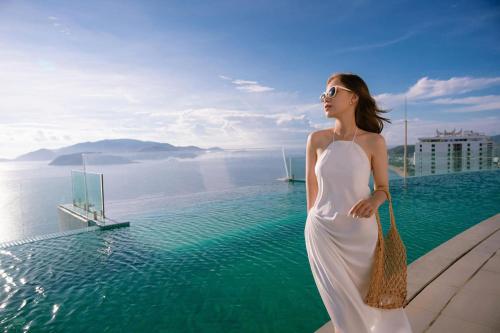 a woman in a white dress standing next to a swimming pool at SeaHaven Panorama Nha Trang Superview Apartments in Nha Trang