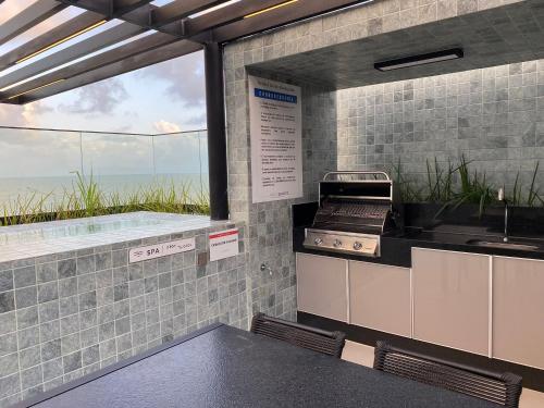 a kitchen with a grill and a view of the ocean at Bela Hospedagem - #Neo Duos 104 in Cabedelo