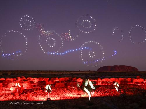 a group of people dancing around a fire at night at The Lost Camel Hotel in Ayers Rock