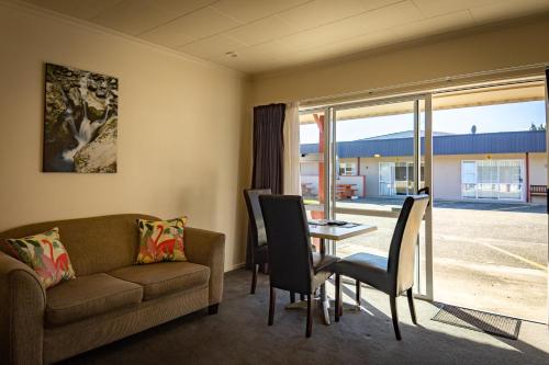 een woonkamer met een bank en een tafel bij Amber Court Motel in Te Anau