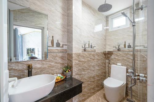 a bathroom with a sink and a toilet and a mirror at Villa Hẻm Đà Lạt in Da Lat