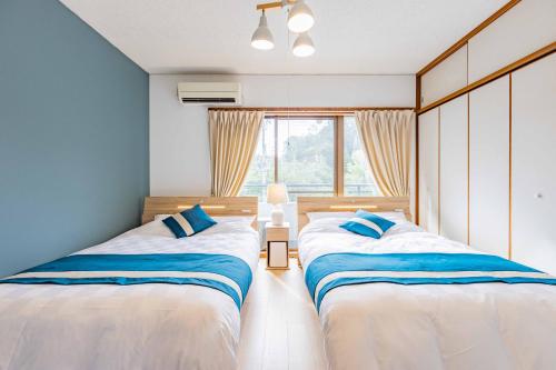 two beds in a room with a window at Azami Ann Maisonette in Shirahama