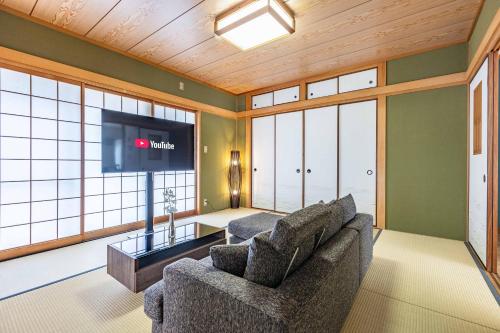 sala de estar con sofá y TV de pantalla plana en Azami Ann Maisonette, en Shirahama