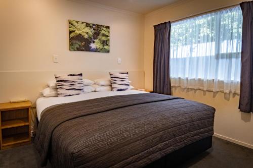 sypialnia z dużym łóżkiem i oknem w obiekcie Amber Court Motel w mieście Te Anau