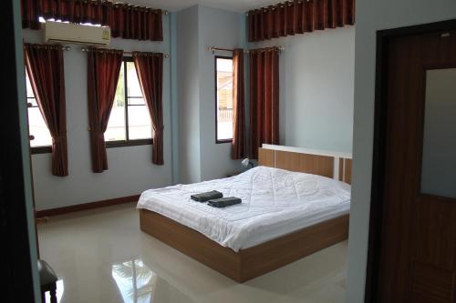 - une chambre avec un lit doté de draps blancs et de fenêtres dans l'établissement Naluemon Village FH 3-4, à Ban Phe