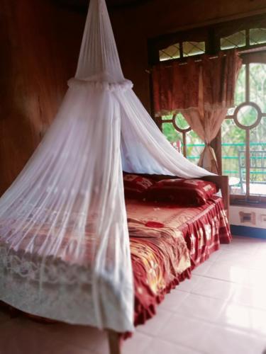 a bedroom with a bed with a mosquito net at WATUGANA BUNGALOW KELIMUTU in Kelimutu