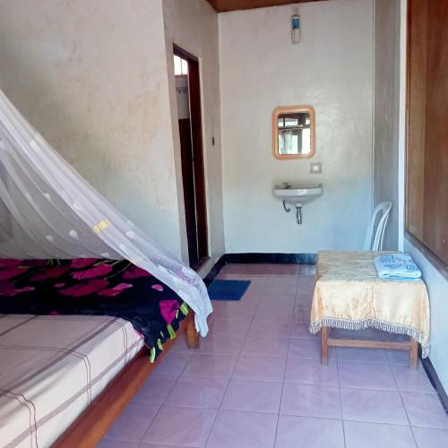 a room with a bed and a sink and a table at WATUGANA BUNGALOW KELIMUTU in Kelimutu